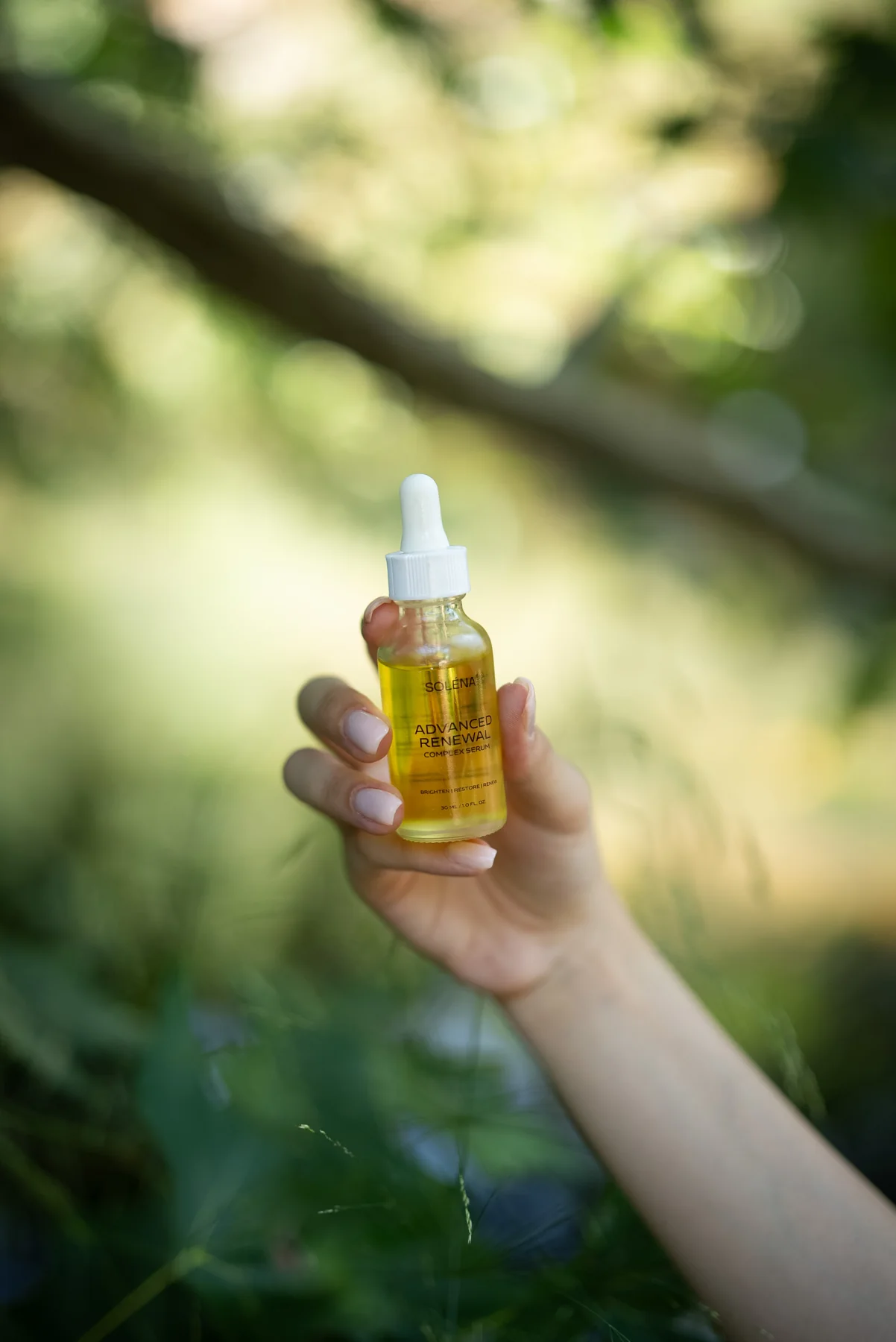 Hand holding SOLÉNA Advanced Renewal Complex Serum outdoors